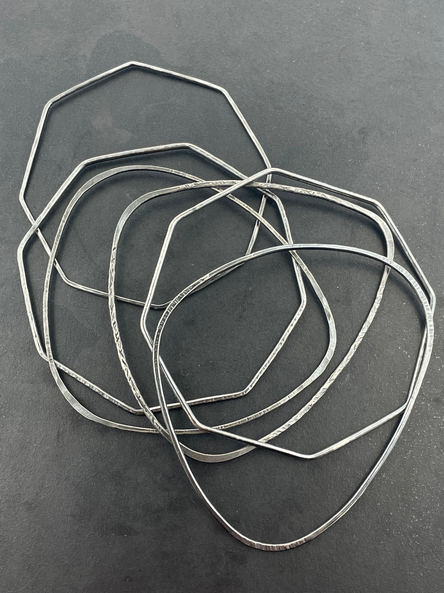 Set of silver stacking bangles on a dark gray background