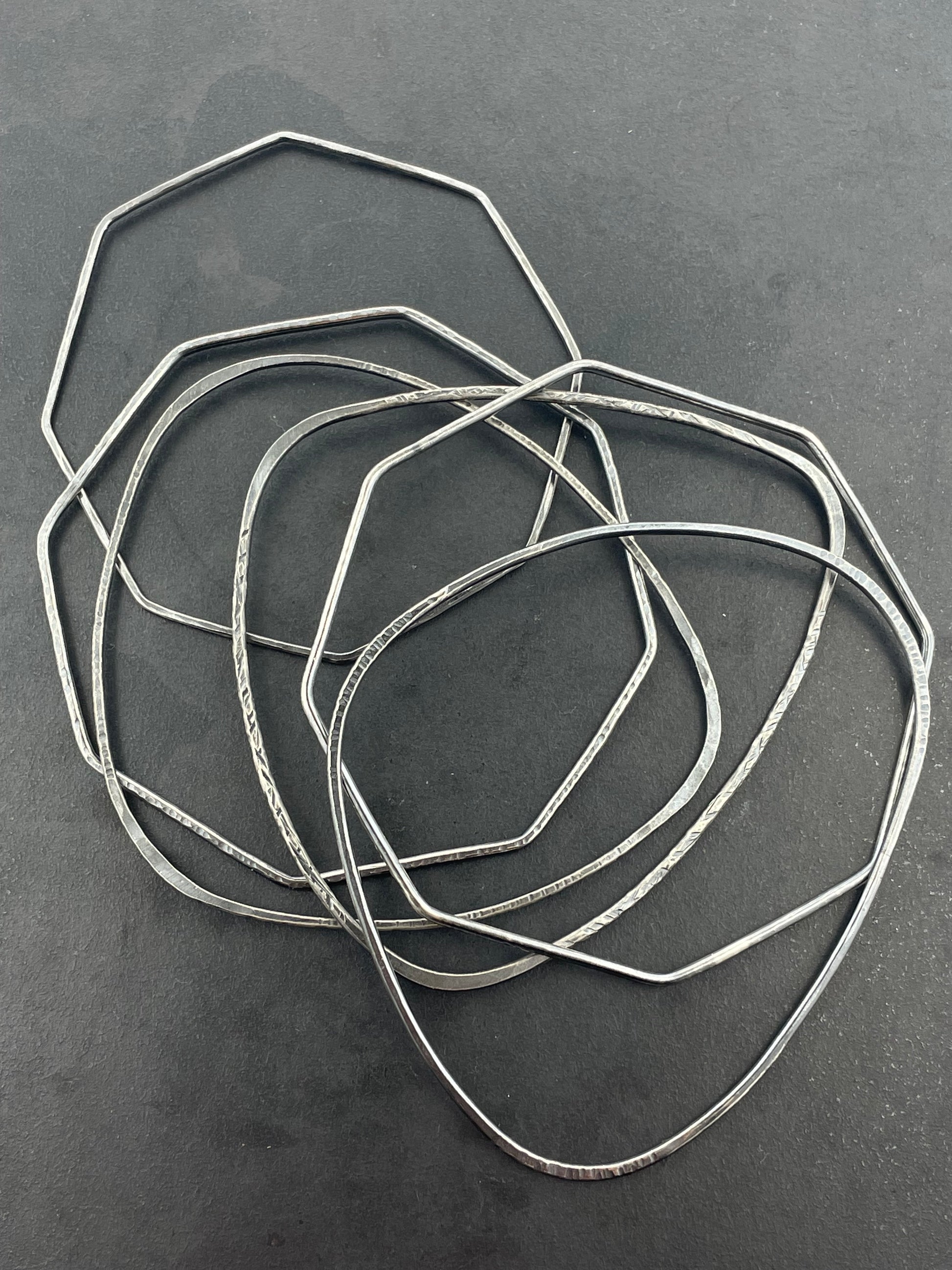 Set of silver stacking bangles on a dark gray background