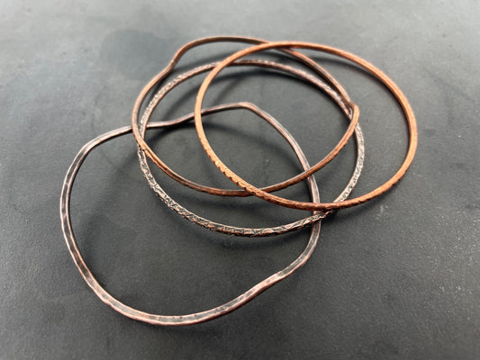 Multiple copper bracelets on a dark gray surface